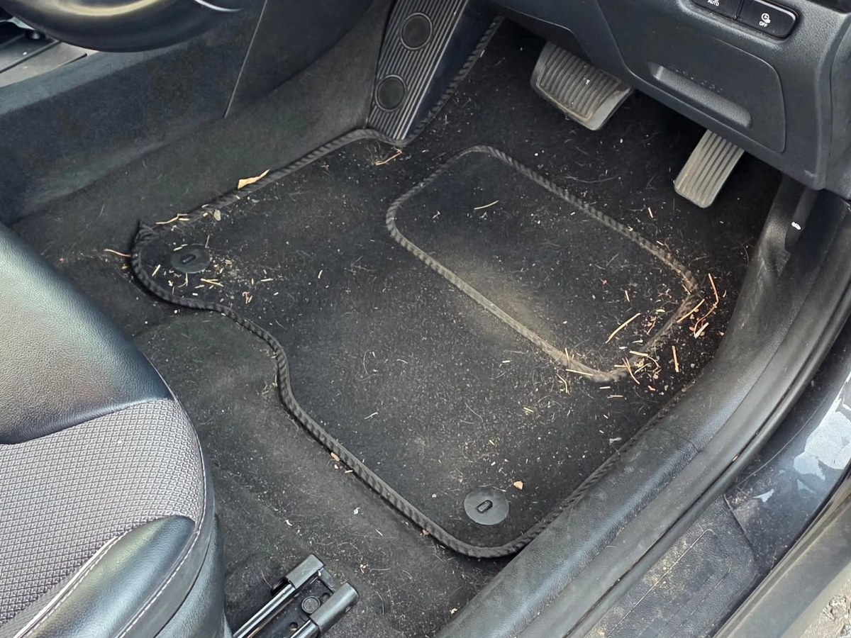 Kia footwell before cleaning, covered in dirt and debris