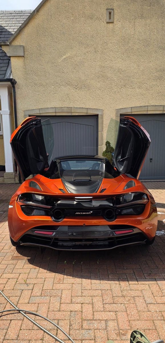 Orange McLaren 720S with both dihedral doors raised after a full detail